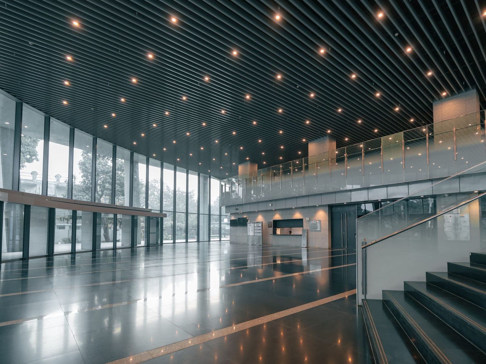 The atrium of a modern commercial building with a stone floor, glass curtain wall and reception desk