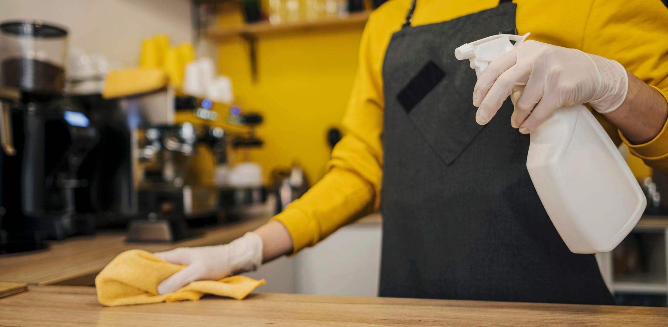 A gloved OLAH technician spraying and wiping down a counter surface